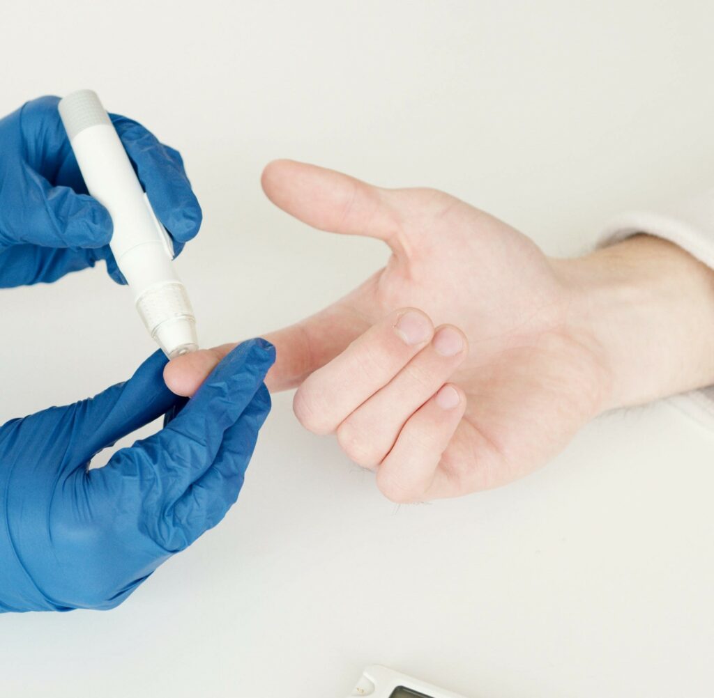 Schritt eins der Blutzuckermessung. Mithilfe eines sicheren Geräts wird in die seitliche Fingerkuppe gestochen.