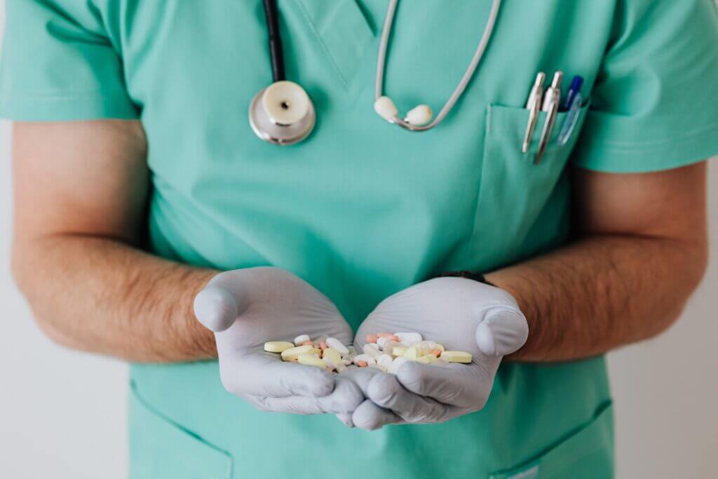 Ein Mediziner hält eine Handvoll Medikamente.