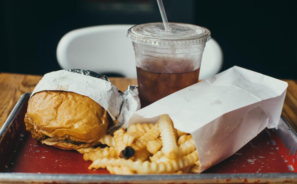 Ein Bild, mit Pommes, Burger und einem Getränk, das wie Cola aussieht.